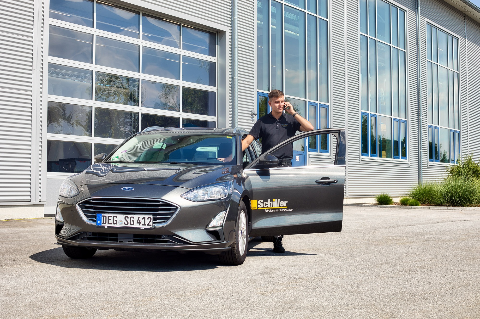 Mitarbeiter telefoniert während er in ein Schiller Firmenauto einsteigt