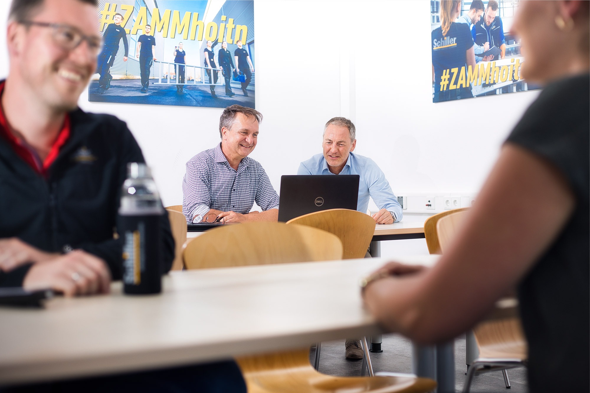 Mitarbeiter bei Schiller im Pausenraum lachen und reden gemeinsam